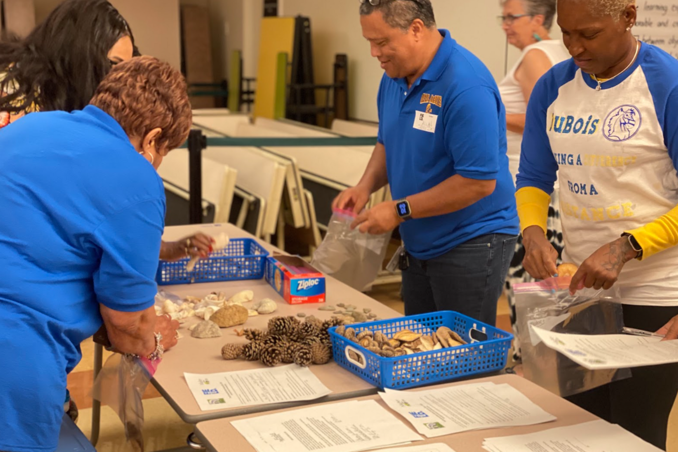 Several people standing around a table with craft supplies and papers.