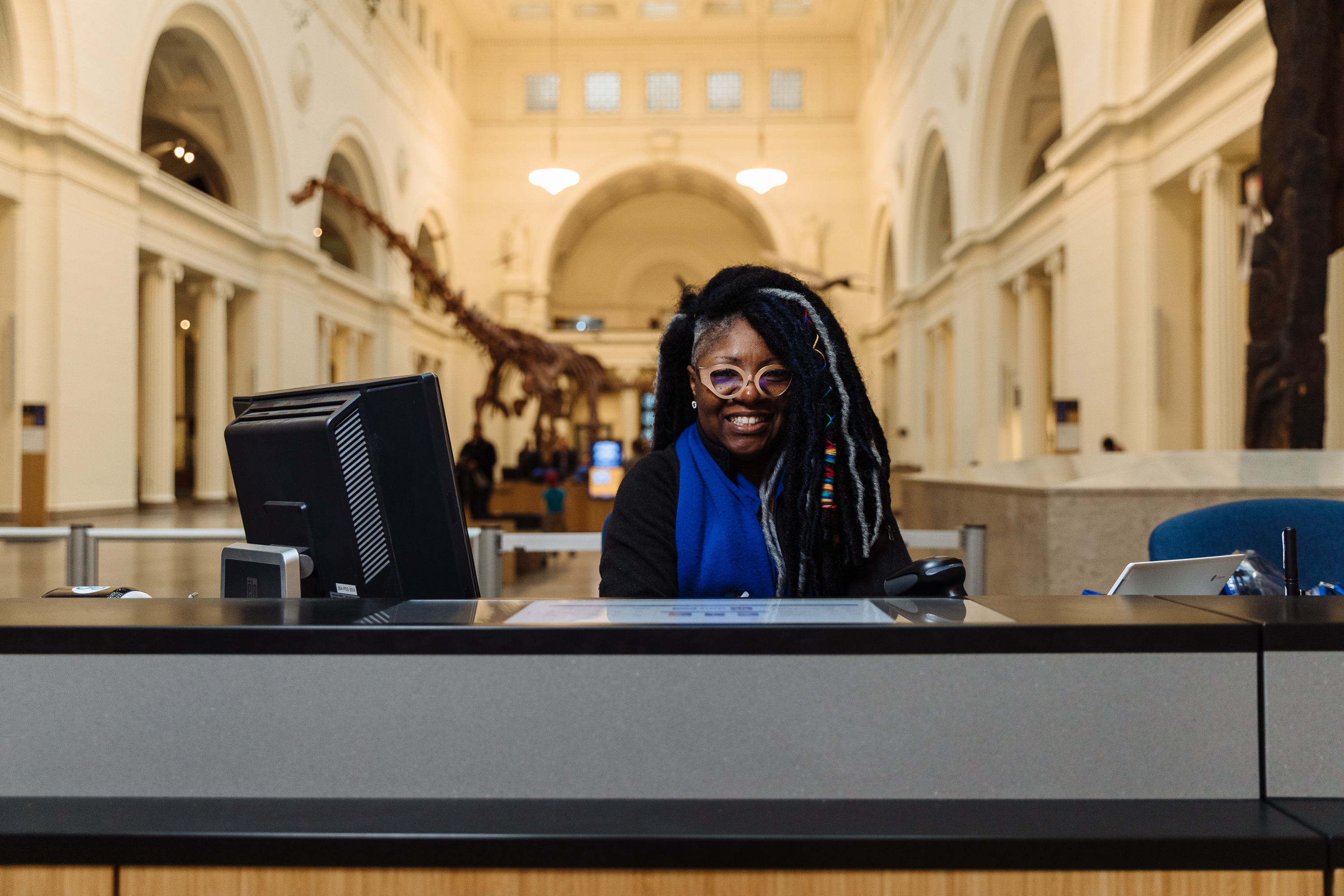 A museum staff member sits at the ticketing desk at the museum's main entrance.