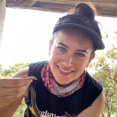 A smiling woman holding a small snake