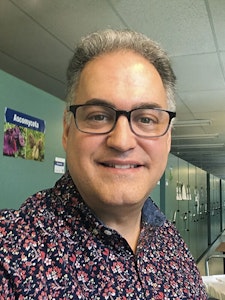 A smiling man with a colorful button-up shirt