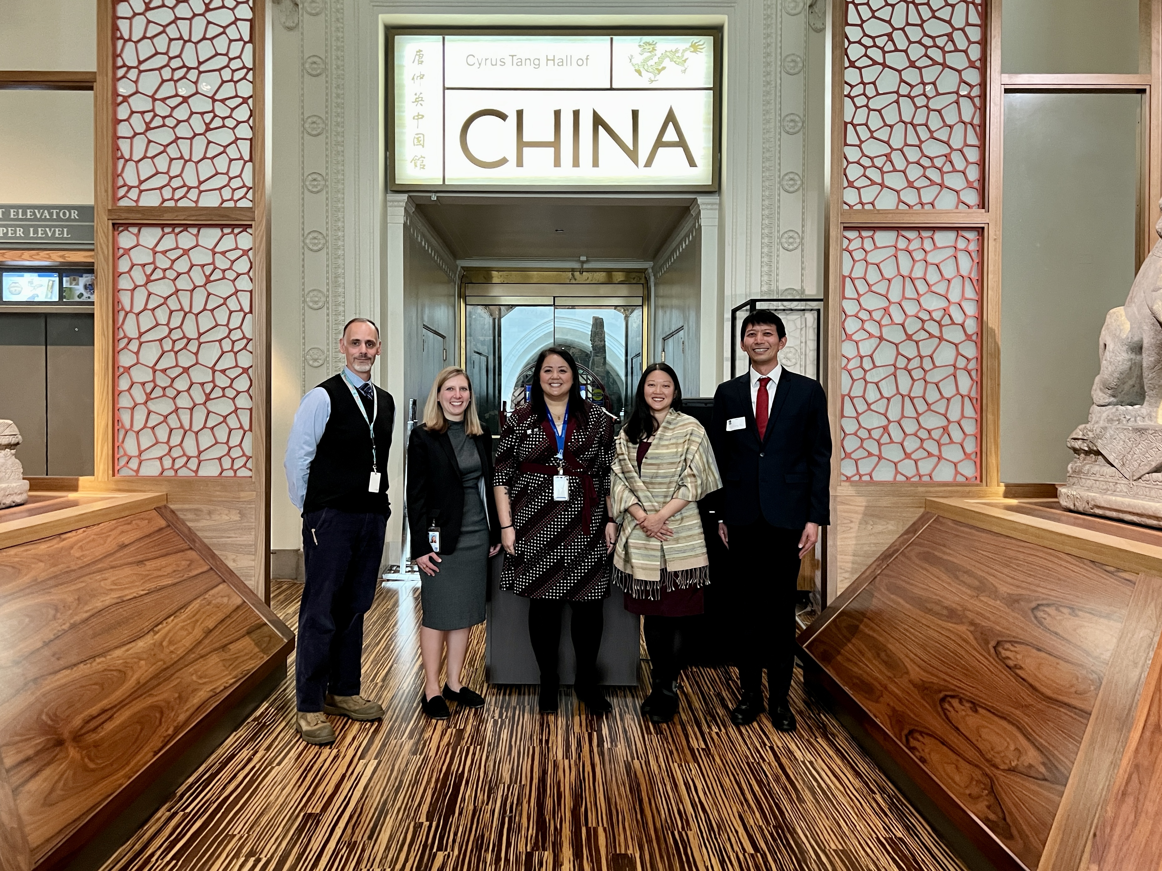 Five people stand next to each other at the entrance to an exhibition hall with a sign with the word China