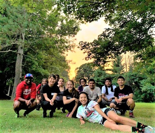 a group of young people pose for a photo under trees