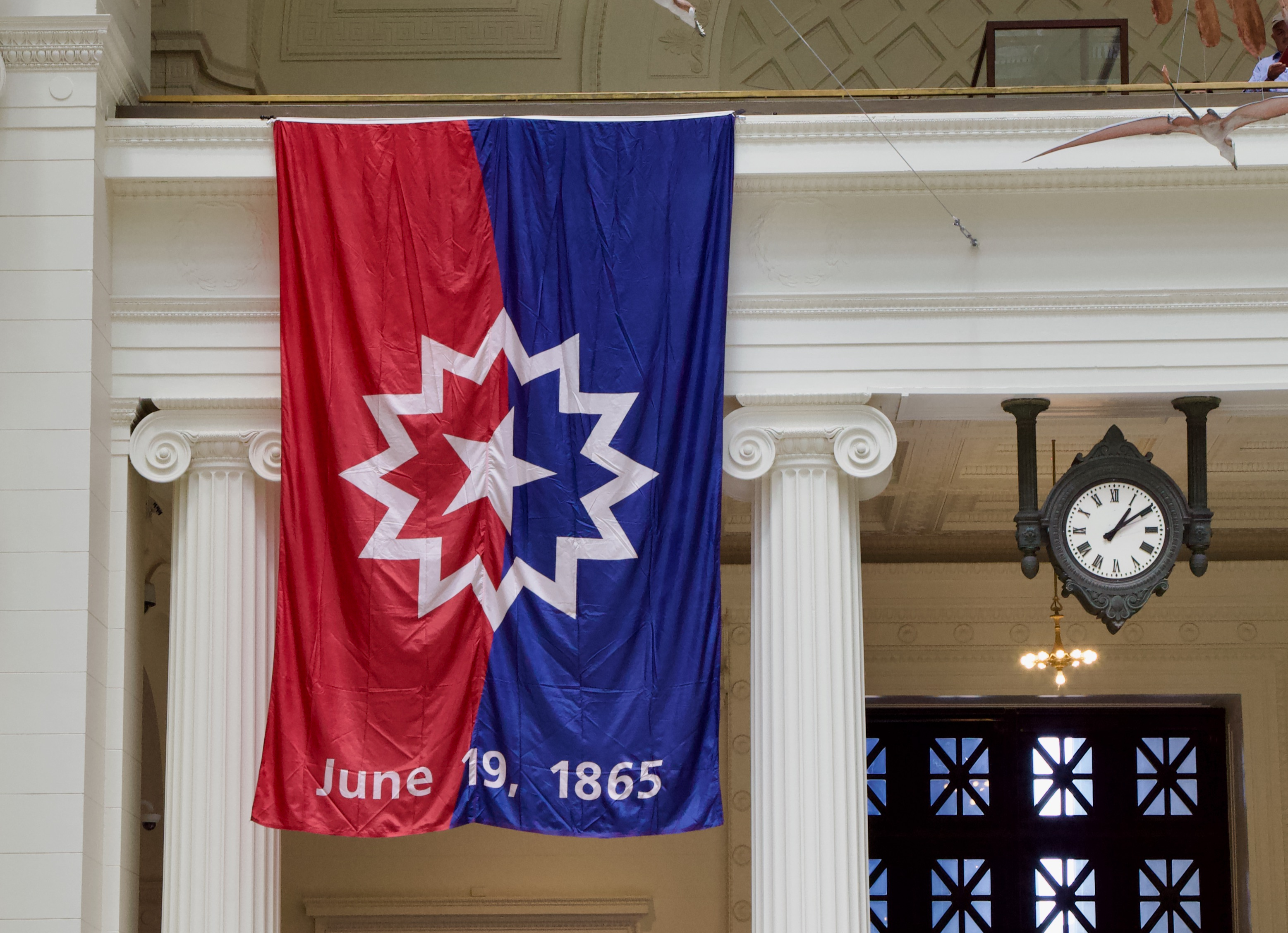The Juneteenth flag hanging from a balcony, a clock nearby