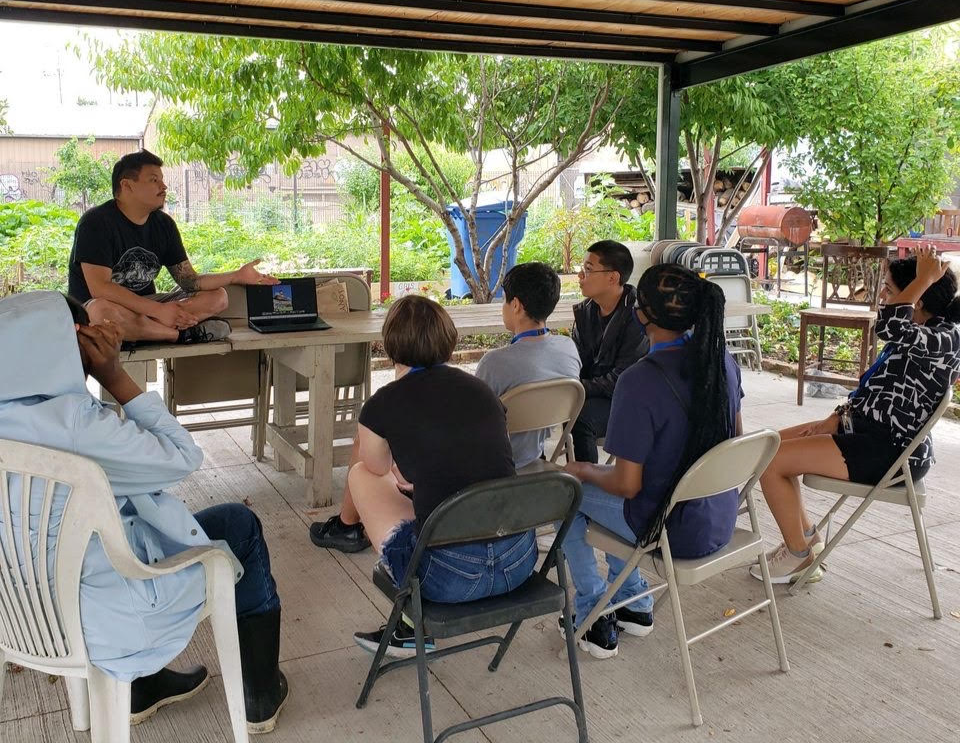 A group seated on chairs outside on a covered deck