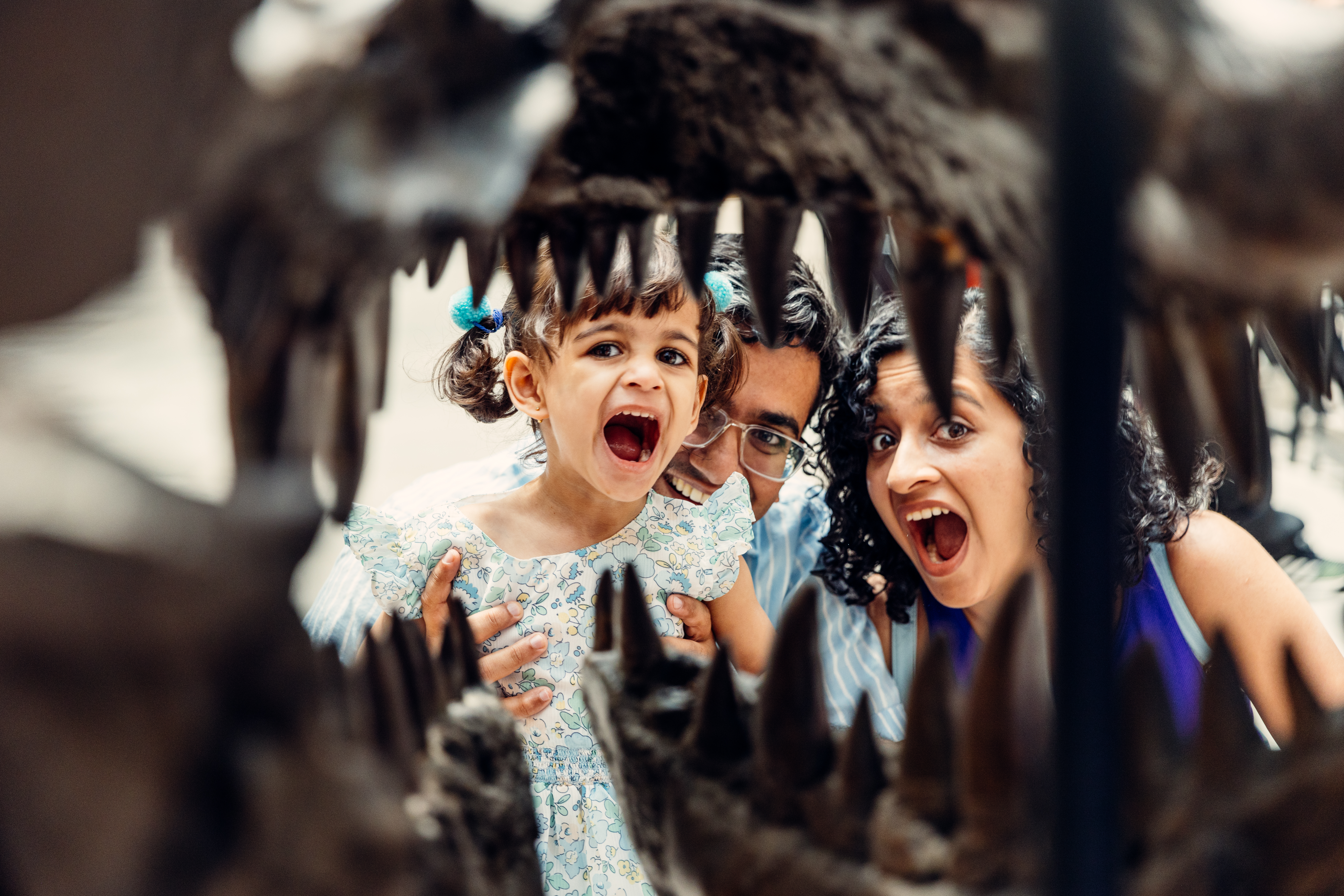 Two adults and a child looking through a large fossil dinosaurs mouth
