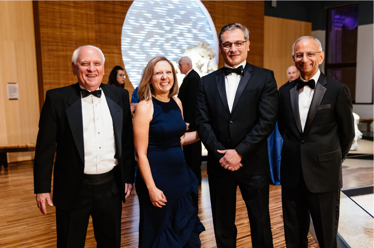 Four people in formal attire stand side-by-side.