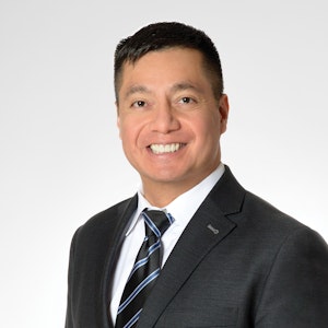 A headshot of a man wearing a dark suit with white shirt and tie.