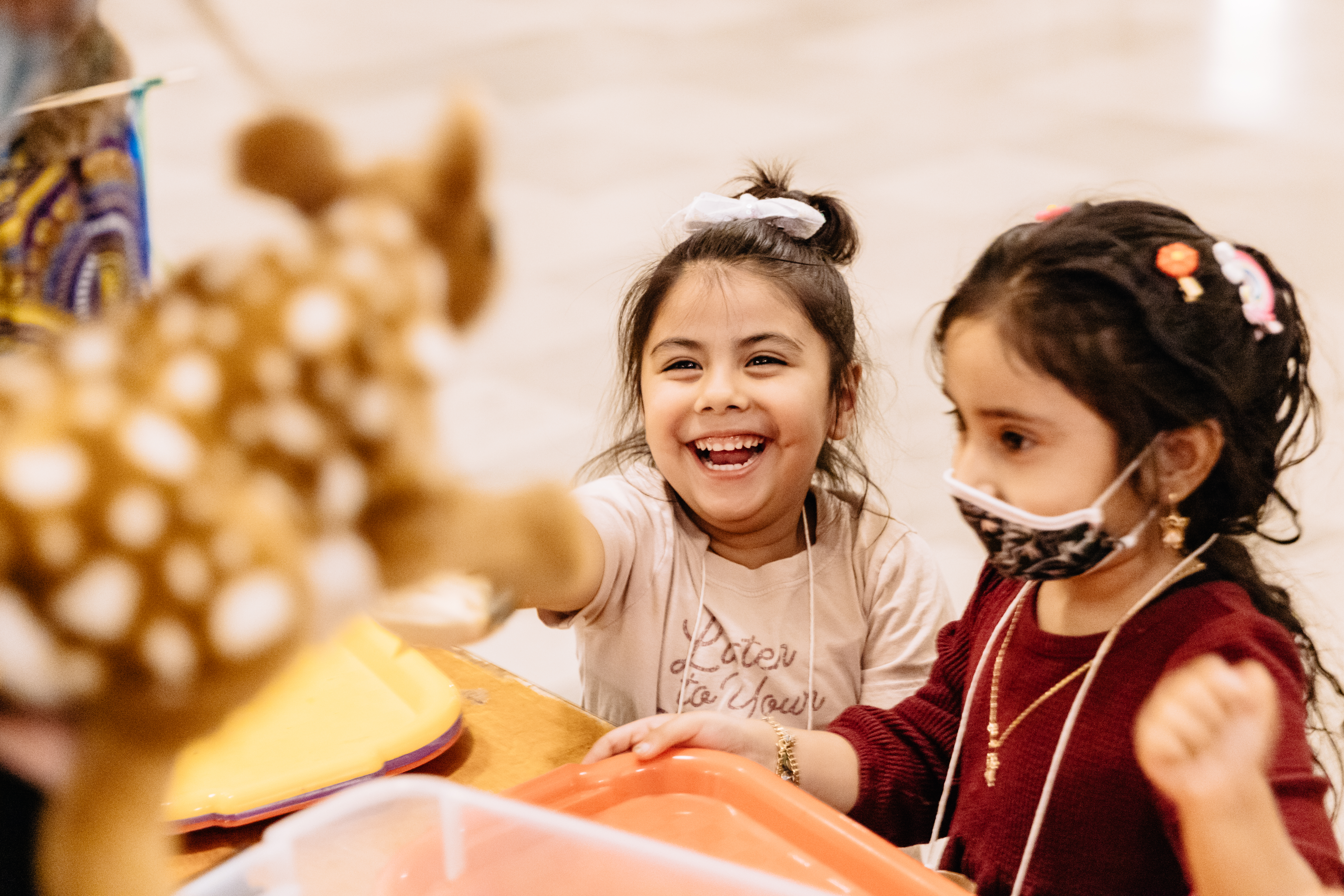 two children, one smiling, one wearing a face mask