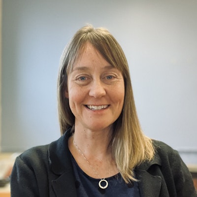 a woman with straight blonde hair wearing a blue top and black blazer