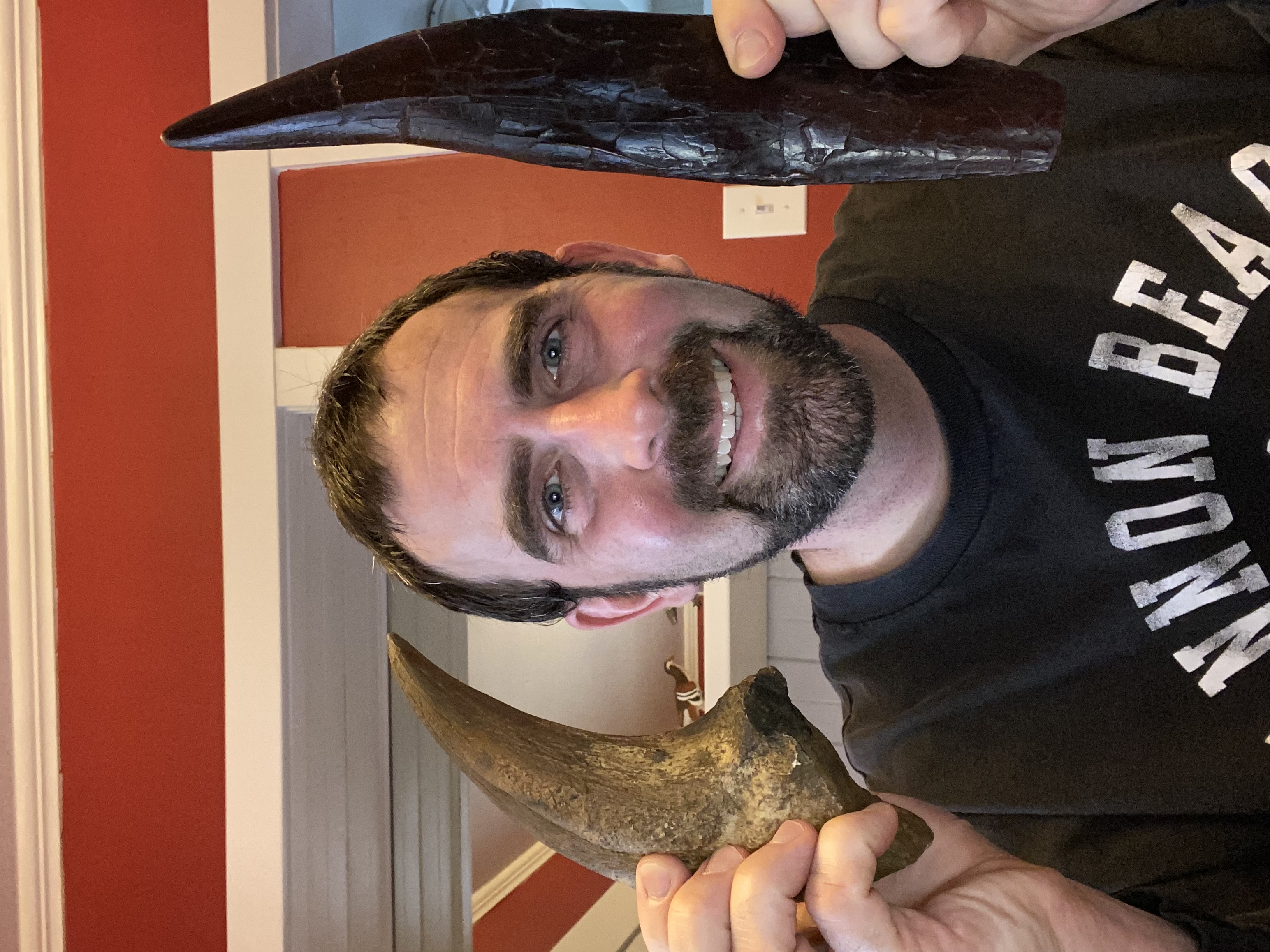 A man holding two large fossil, one on each side of his head.