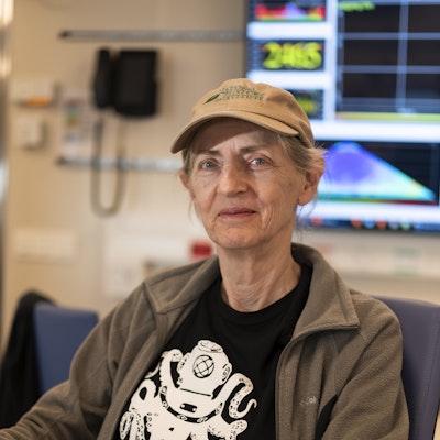 A woman wearing a cap and jacket, sitting at a table.