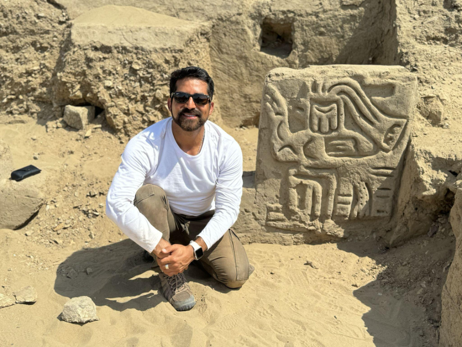 A Field Museum scientist kneels with the carving of a mythological bird creature