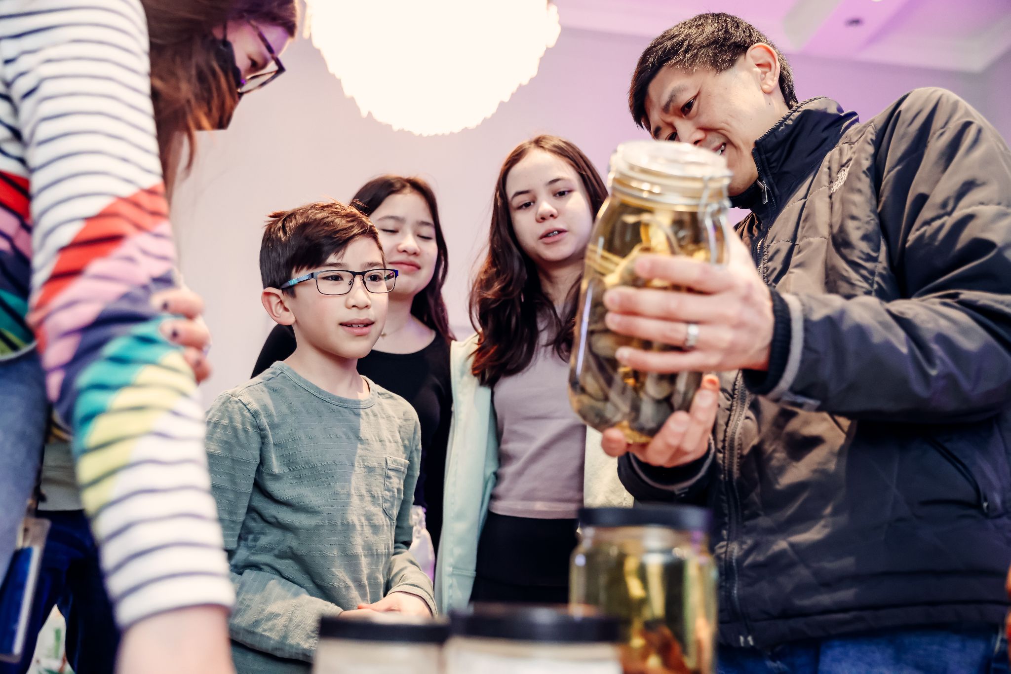 A group of visitors interact with museum specimens in glass jars.