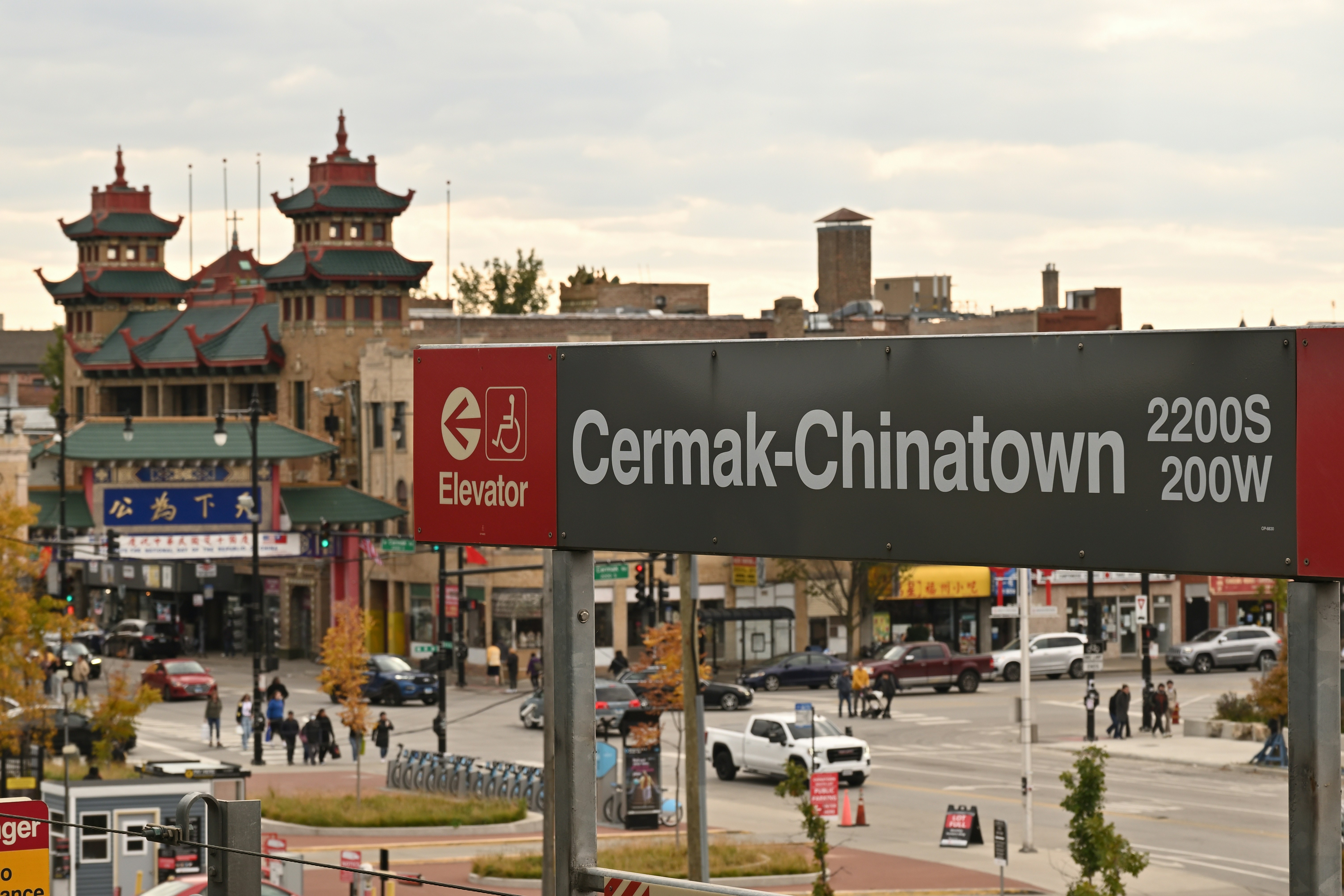 The sign at a Cermak-Chinatown train stop, with a city's Chinatown neighborhood in the background.