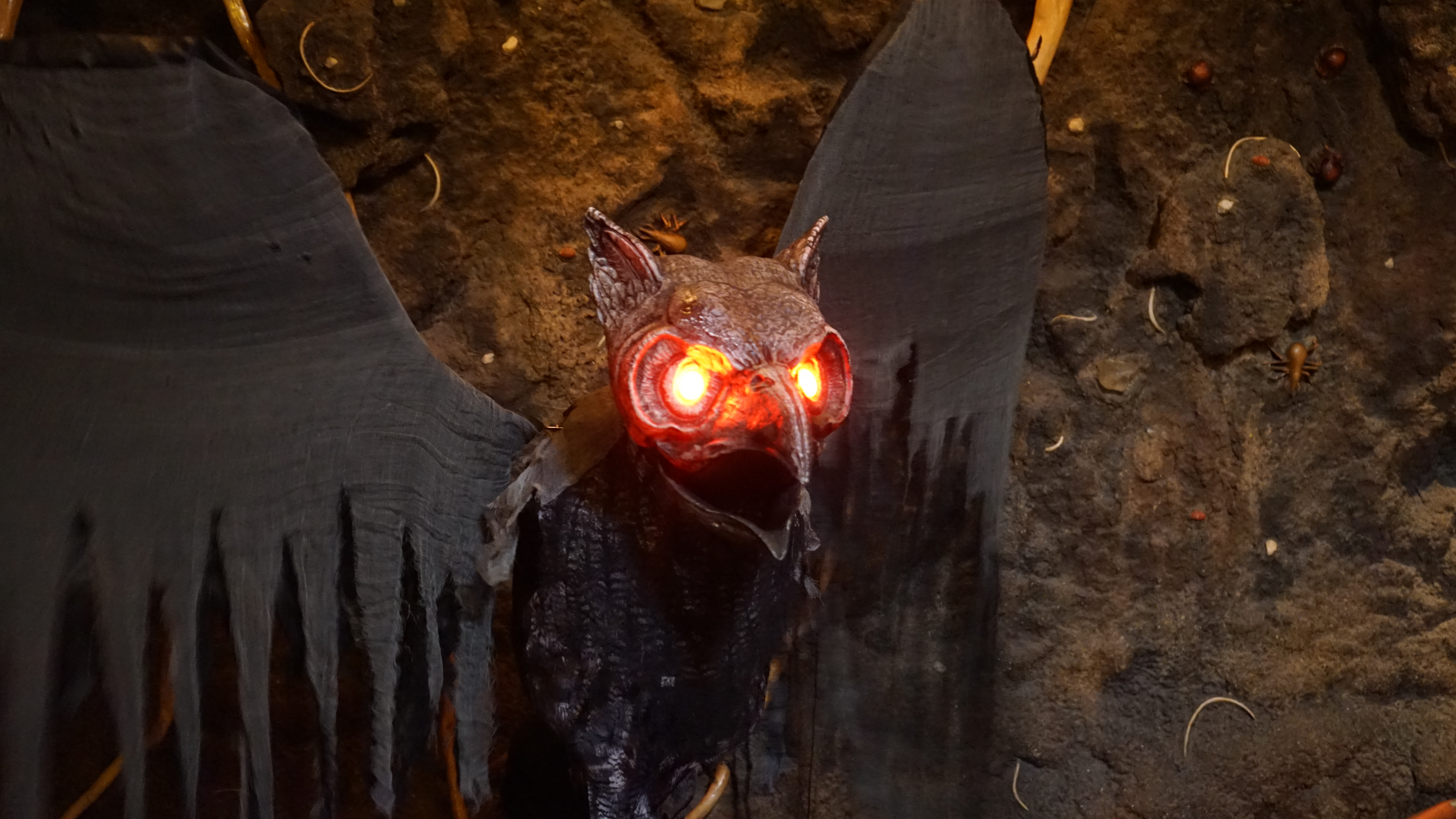 An animated owl with red, light-up eyes used as a halloween decoration