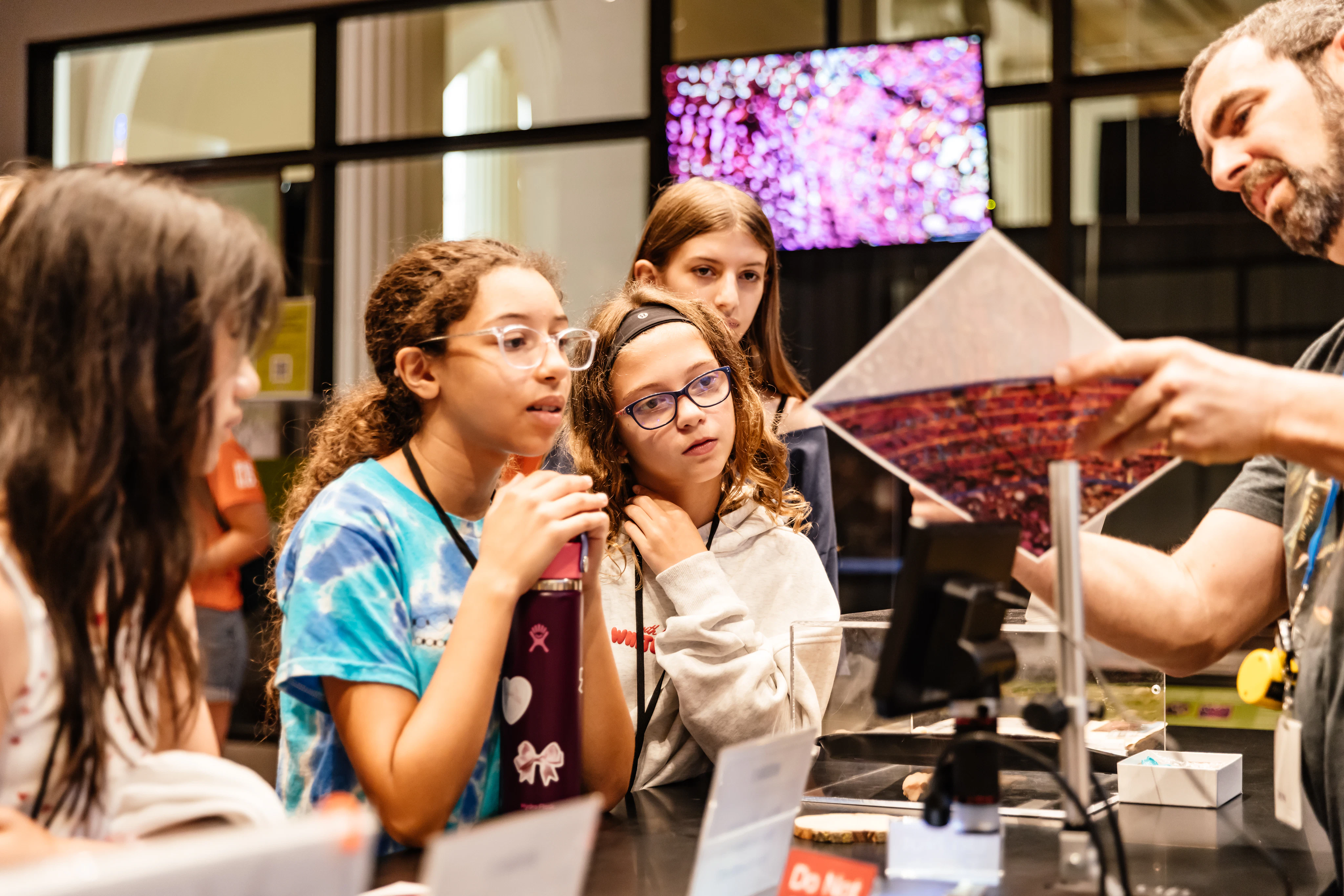 A group of students look on as a man shares an image with them during an activity in the museum.