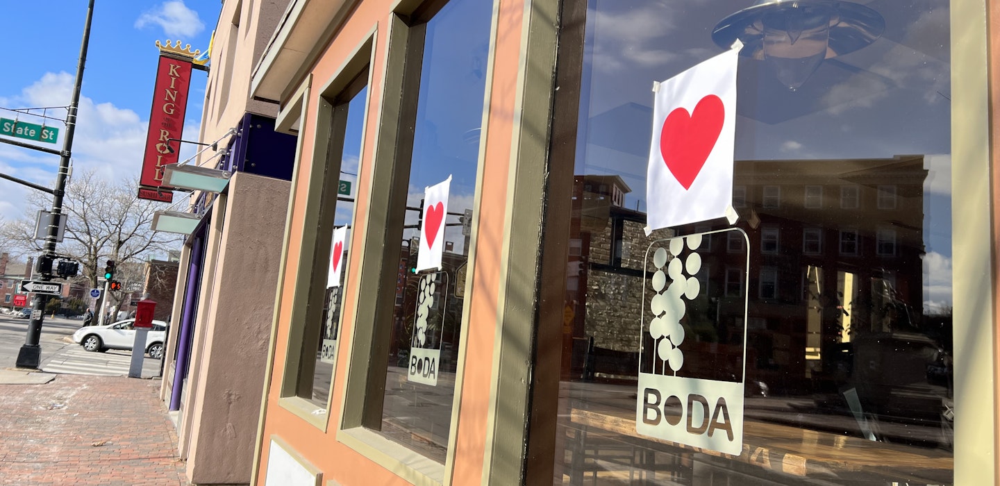 red hearts printed on pieces of white paper are taped on every window of a restaurant
