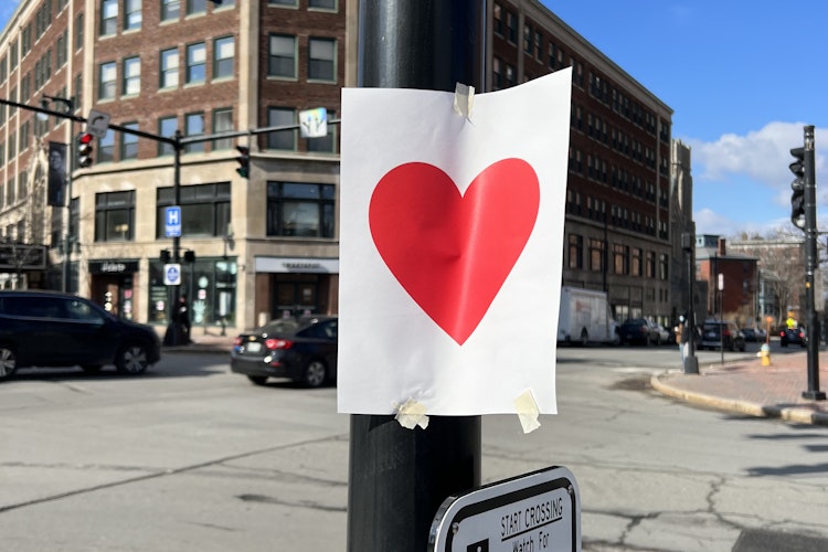 a red heart printed on a piece of white paper is taped to a piece of a pole in Portland