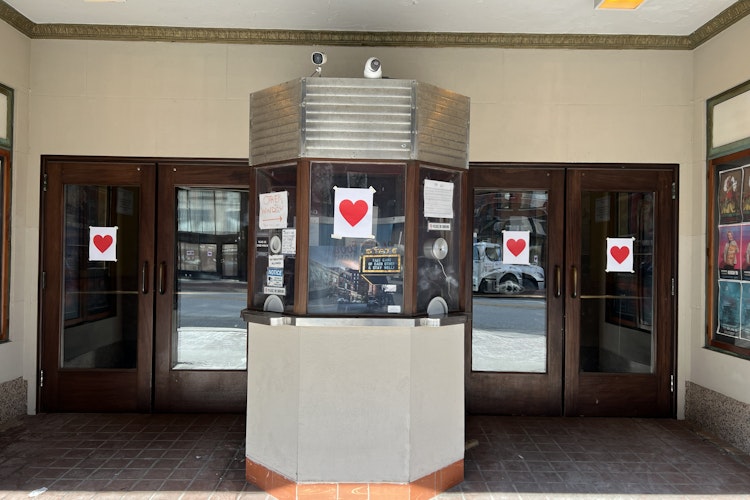 red hearts printed on a piece of white paper are taped on every window of Portland's State Theater
