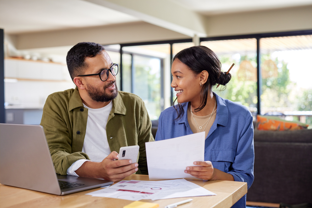 Couple looking at eachother with phone and bills in hand