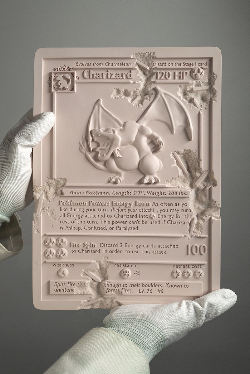Gloved hands holding an eroded pink Charizard Pokemon card