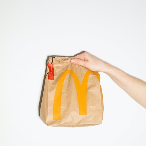 Main tenant un sac en papier d'une franchise Mcdonald's