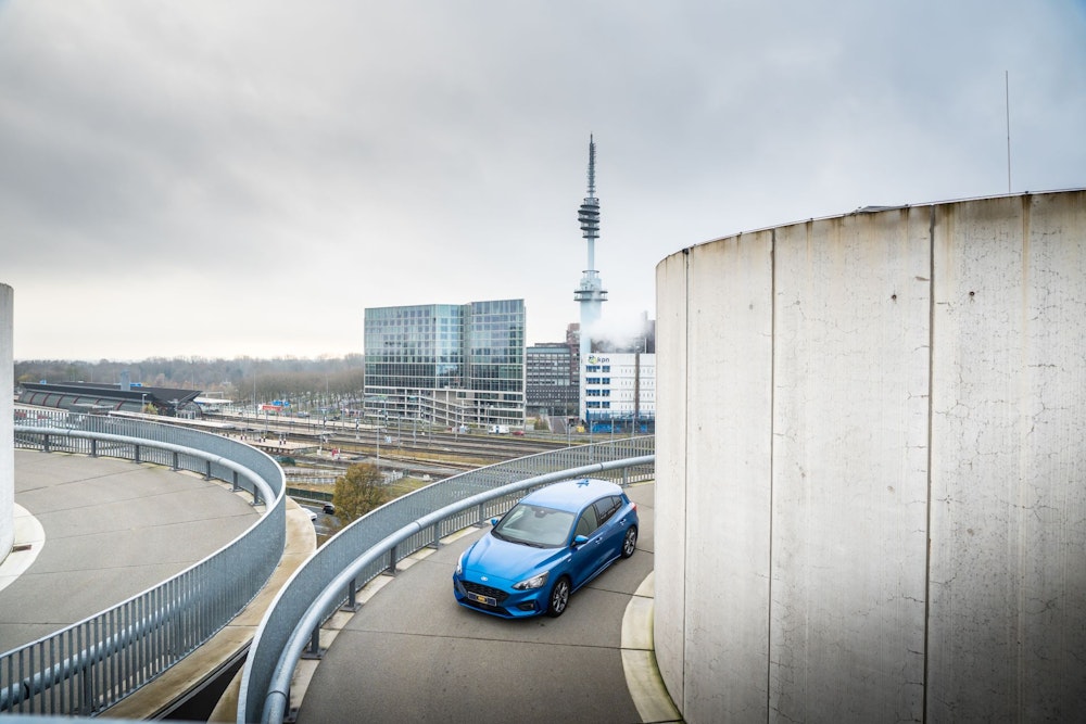 blauwe personenauto rijdt naar beneden in parkeergarage