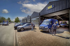 Twee mannen bij een geparkeerde auto en bus van DIKS autoverhuur in Amsterdam Zuidoost.