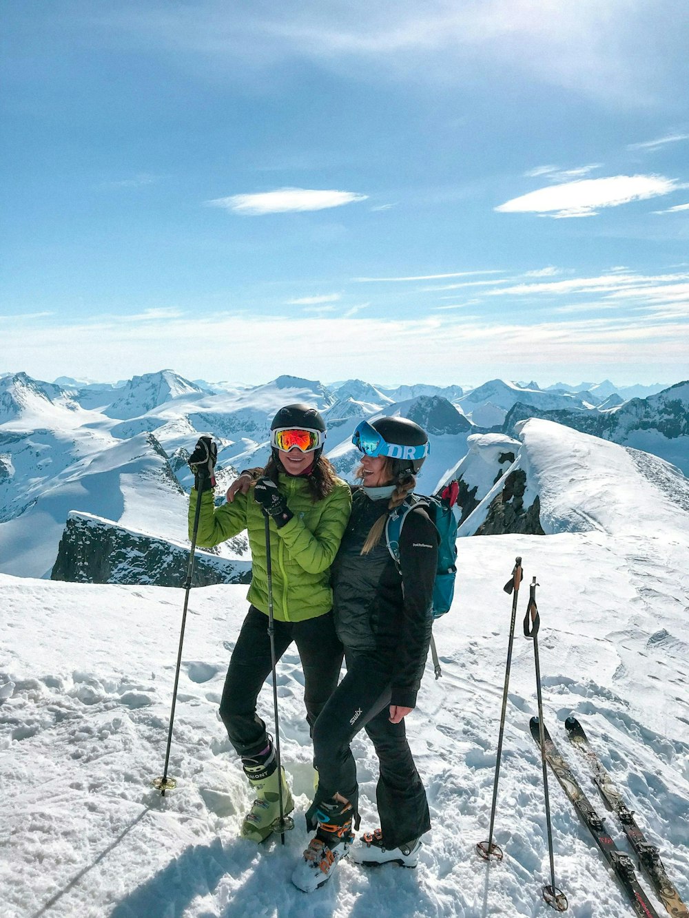 Twee lachende mensen in wintersportkleding op een besneeuwde berg