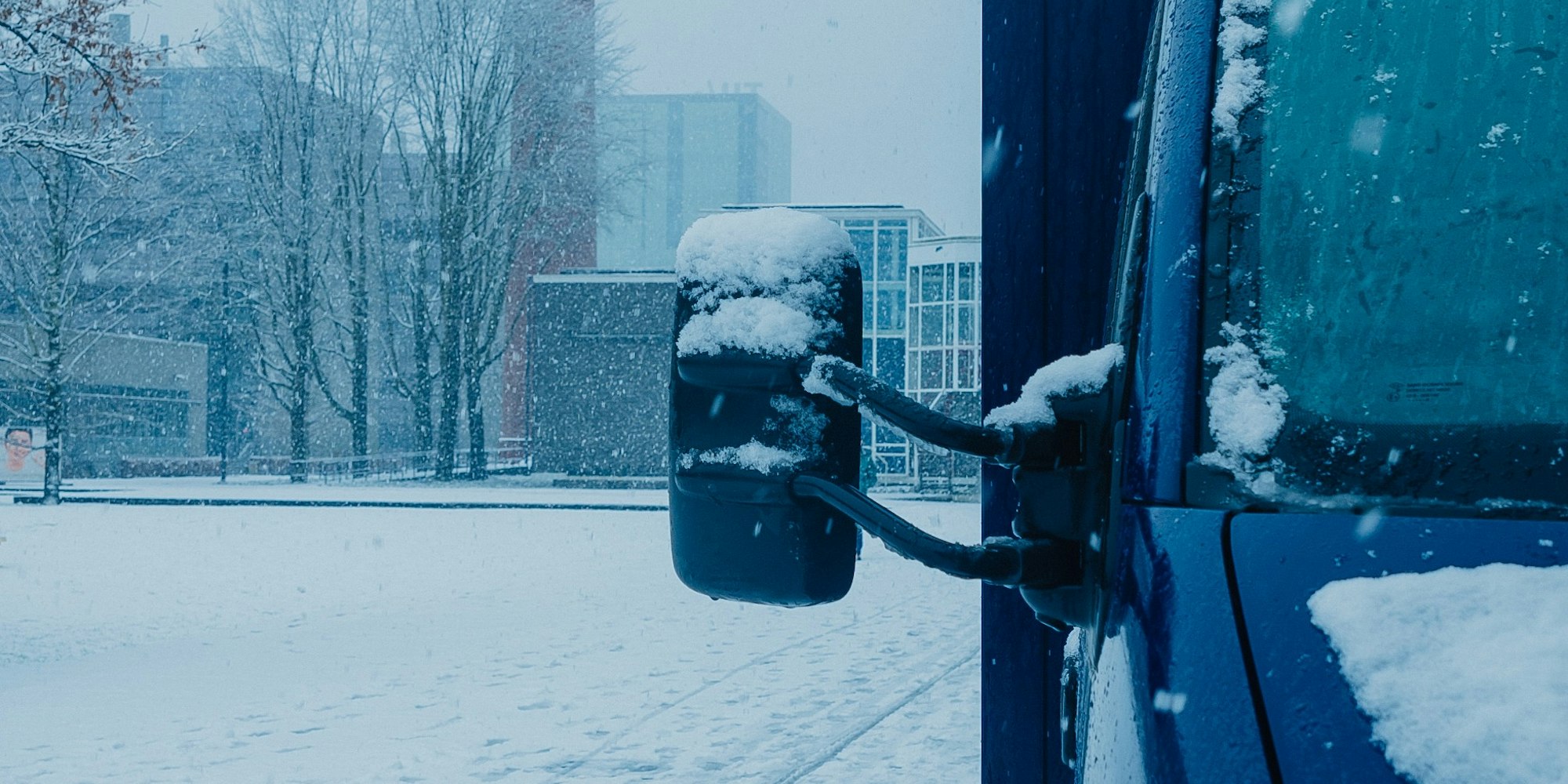 blauwe bus staat in amsterdam, hevige sneeuwval