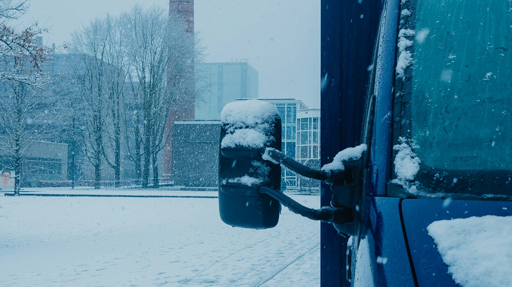 blauwe bus staat in amsterdam, hevige sneeuwval