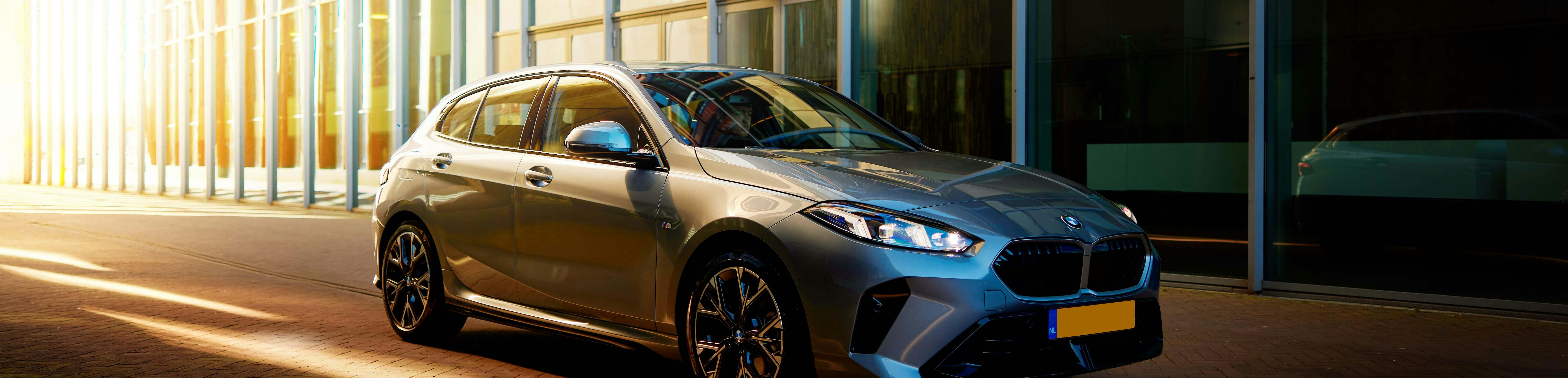 BMW 1-Serie Shortlease BMW Hatchback short-lease at DIKS in Amsterdam, parked in front of a modern glass office building.