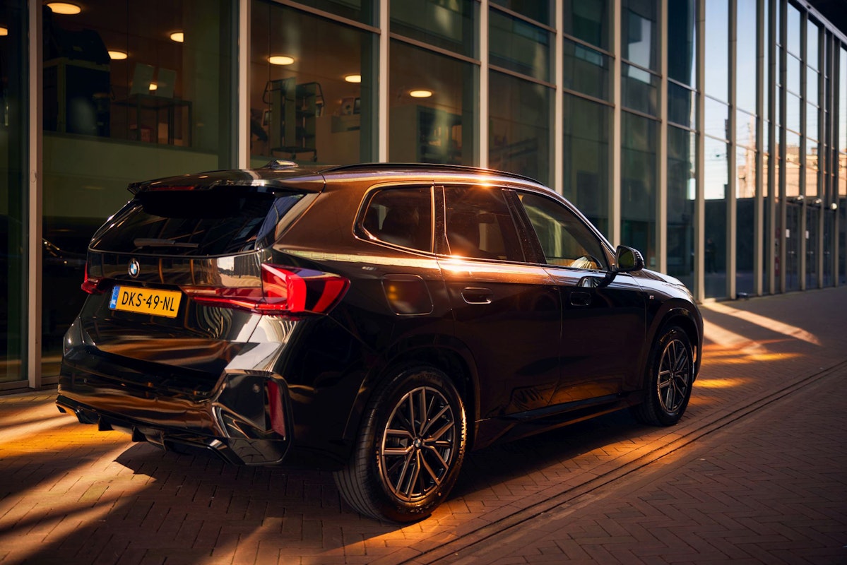 BMW SUV short-lease at DIKS in Amsterdam, parked in front of a modern glass office building.