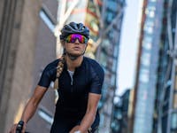 woman cyclist in an urban setting wearing SunGod purple lens sunlgasses