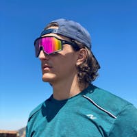 man with backward cap in an outdoor setting wearing SunGod pink lens sunglasses