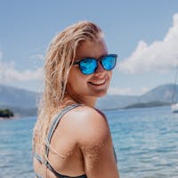 woman wearing SunGod blue lens sunglasses in a coastal setting