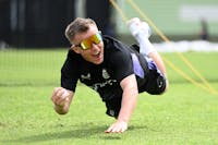 Player catching a cricket ball while falling on the ground