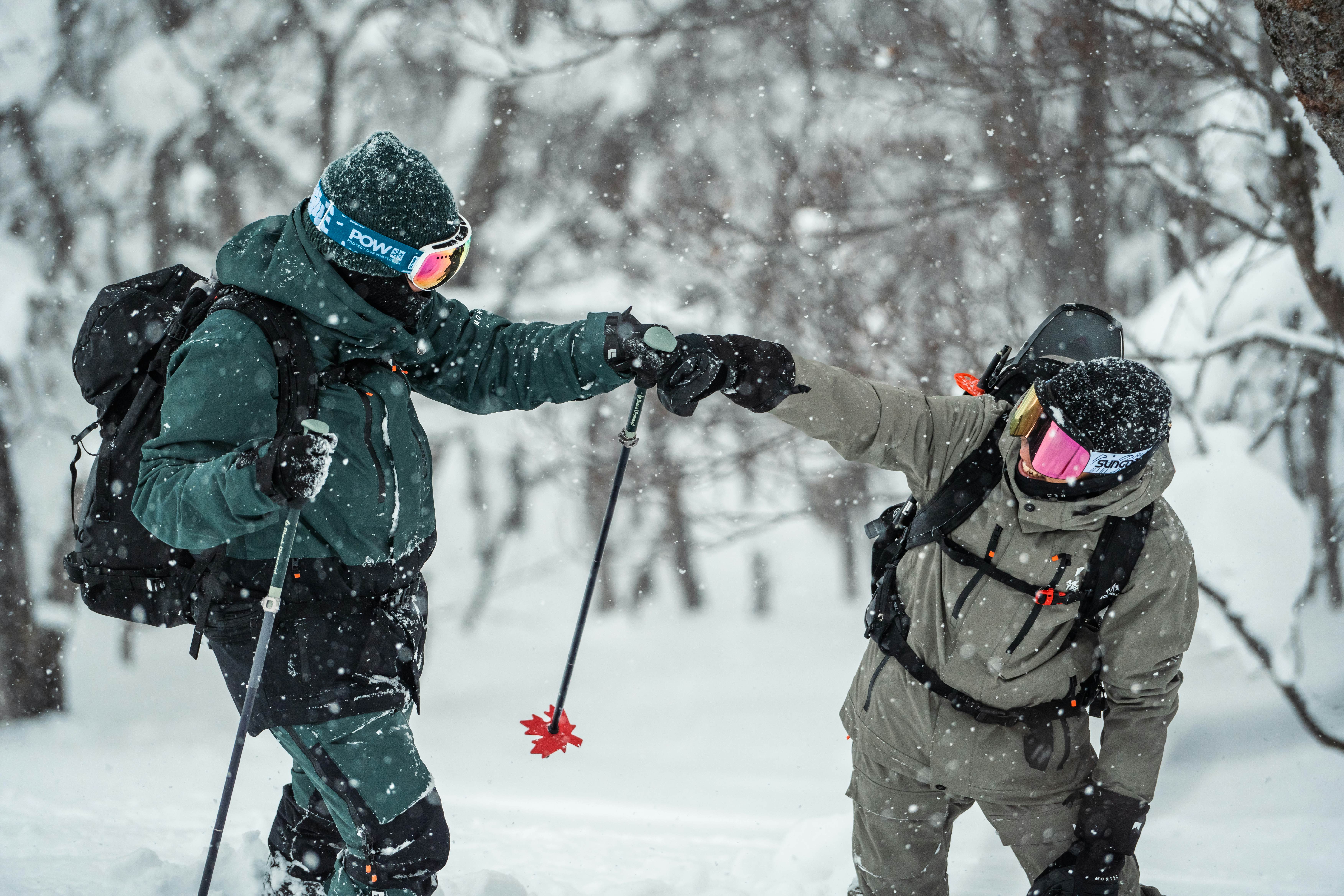 Two skiers fist bump in the backcountry