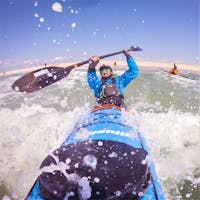 man battling the waves in canoe sunglasses with a green lens