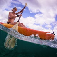 woman wearing orange lens kayak sunglasses paddling across open water