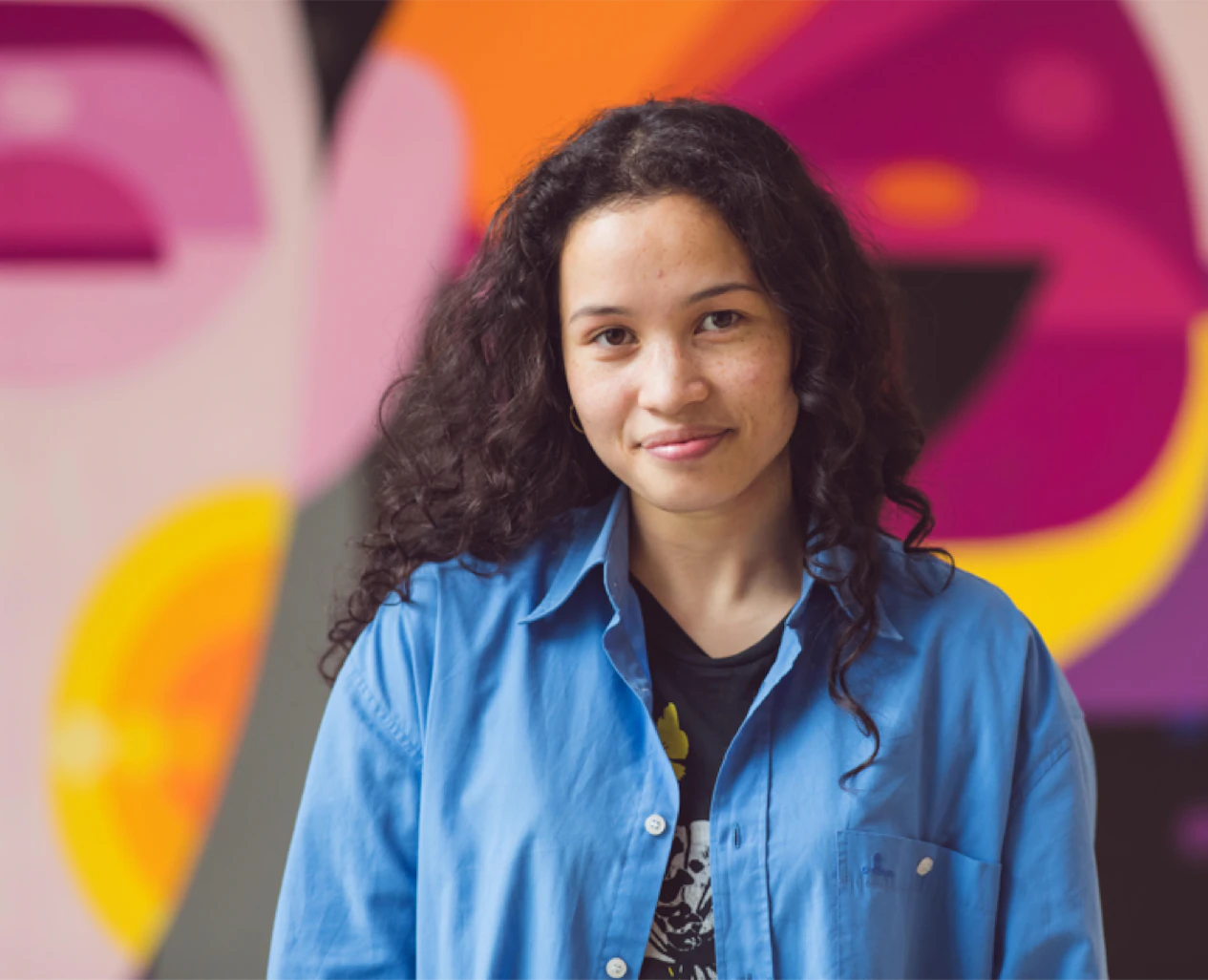 Woman smiling in front of coloured wall