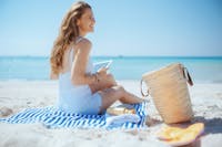 woman sitting on the beach in white outfit