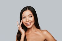 model with dark hair touching cheek with finger