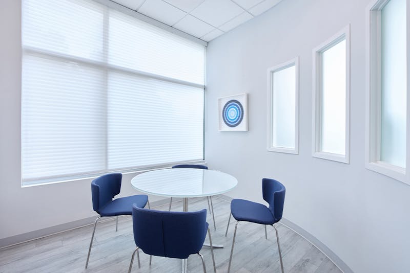 4 blue chairs around a small, white round table