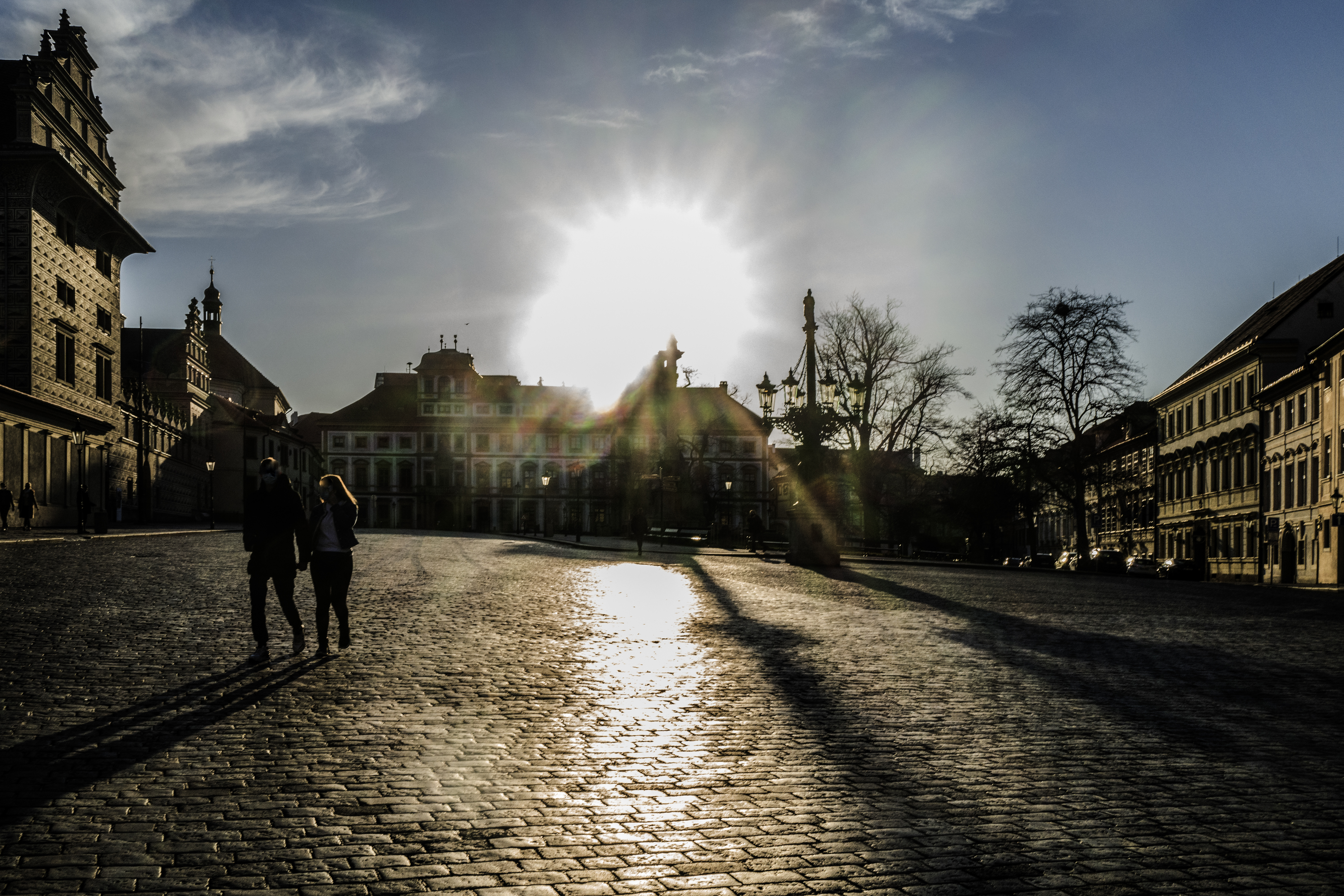 Zářící slunce nad Hradčanským náměstím v Praze, které je v době koronavirové pandemie téměř prázdné
