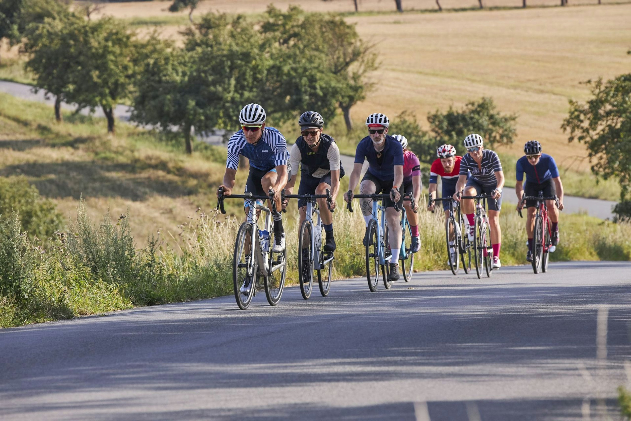 Cyklisté jedou po silnici mezi poli během závodu L’Etape Czech Republic by Tour de France