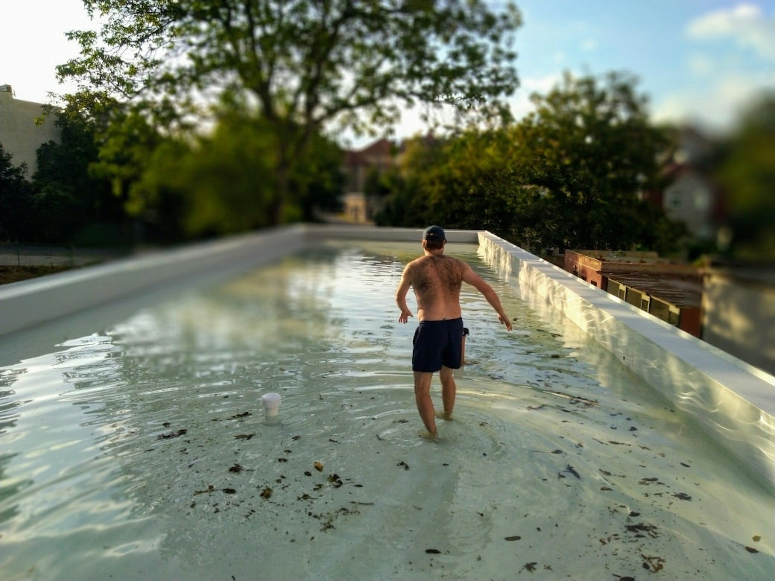 Muž v plavkách stojí ve vodě při záplavové zkoušce zelené střechy nové skautské klubovny v Teplicích