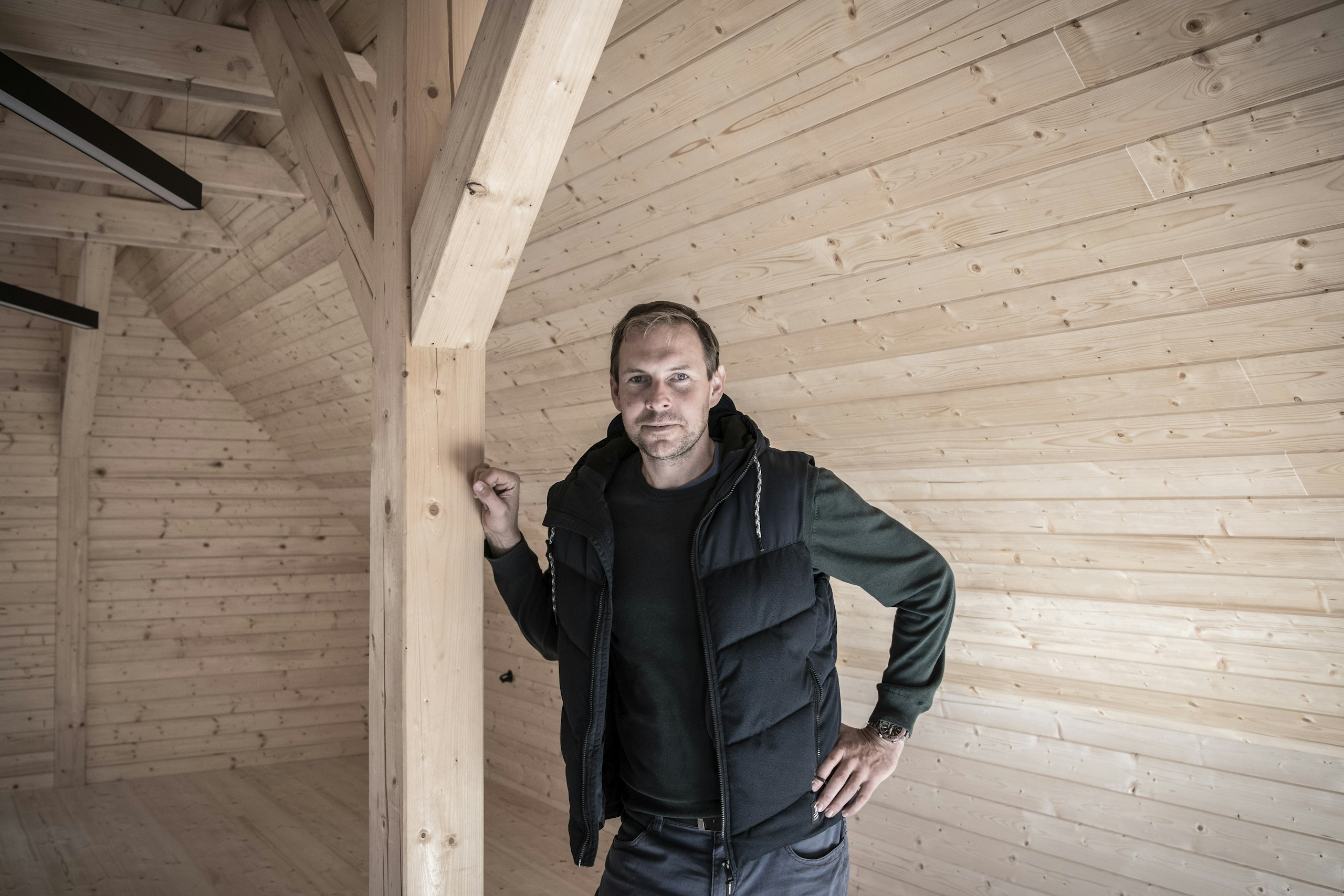 Skaut a architekt Tomáš Rajtora v dřevěném interiéru nové skautské klubovny v Říčanech