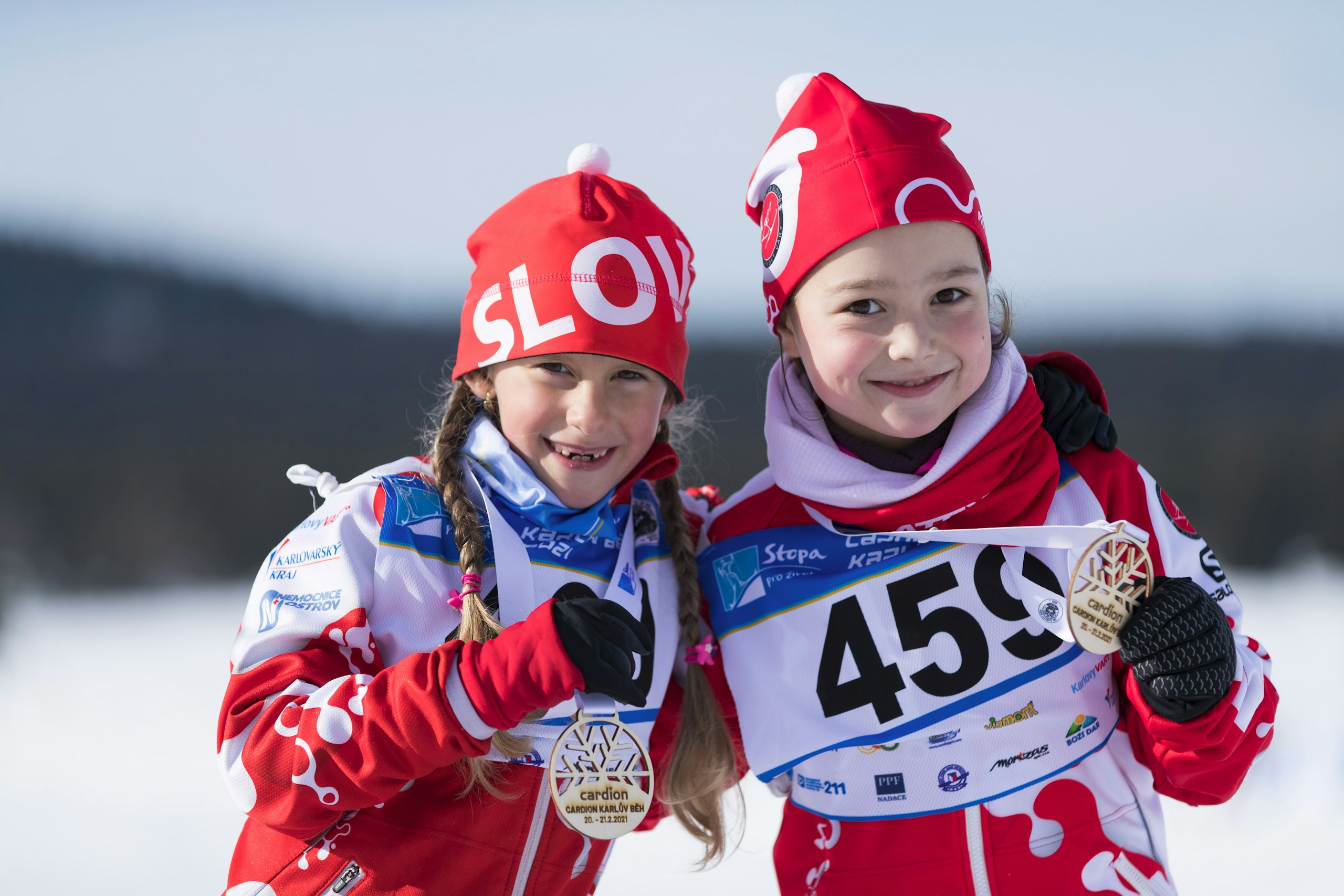 Dvě dívky s medailemi v cíli běžkařského závodu Karlův běh ze seriálu Stopa pro život