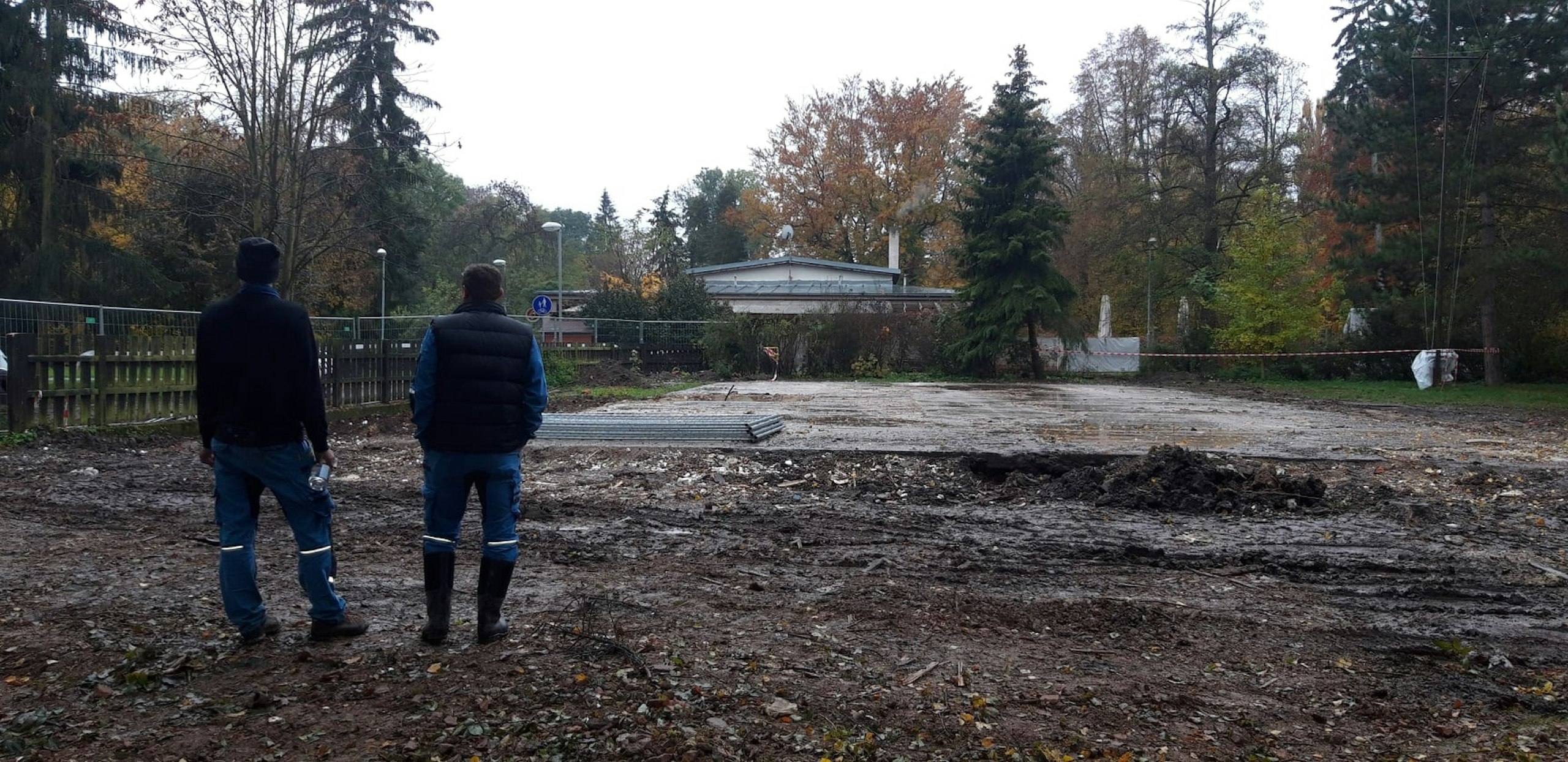 Dva stavební dělníci stojí na prázdné parcele připravené pro stavbu nového skautského domu ve Vyškově